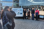 Image shows group of people standing next to an e-cargo bike having their photo taken by photographer 