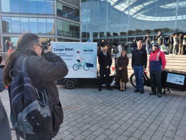 Image shows group of people standing next to an e-cargo bike having their photo taken by photographer 